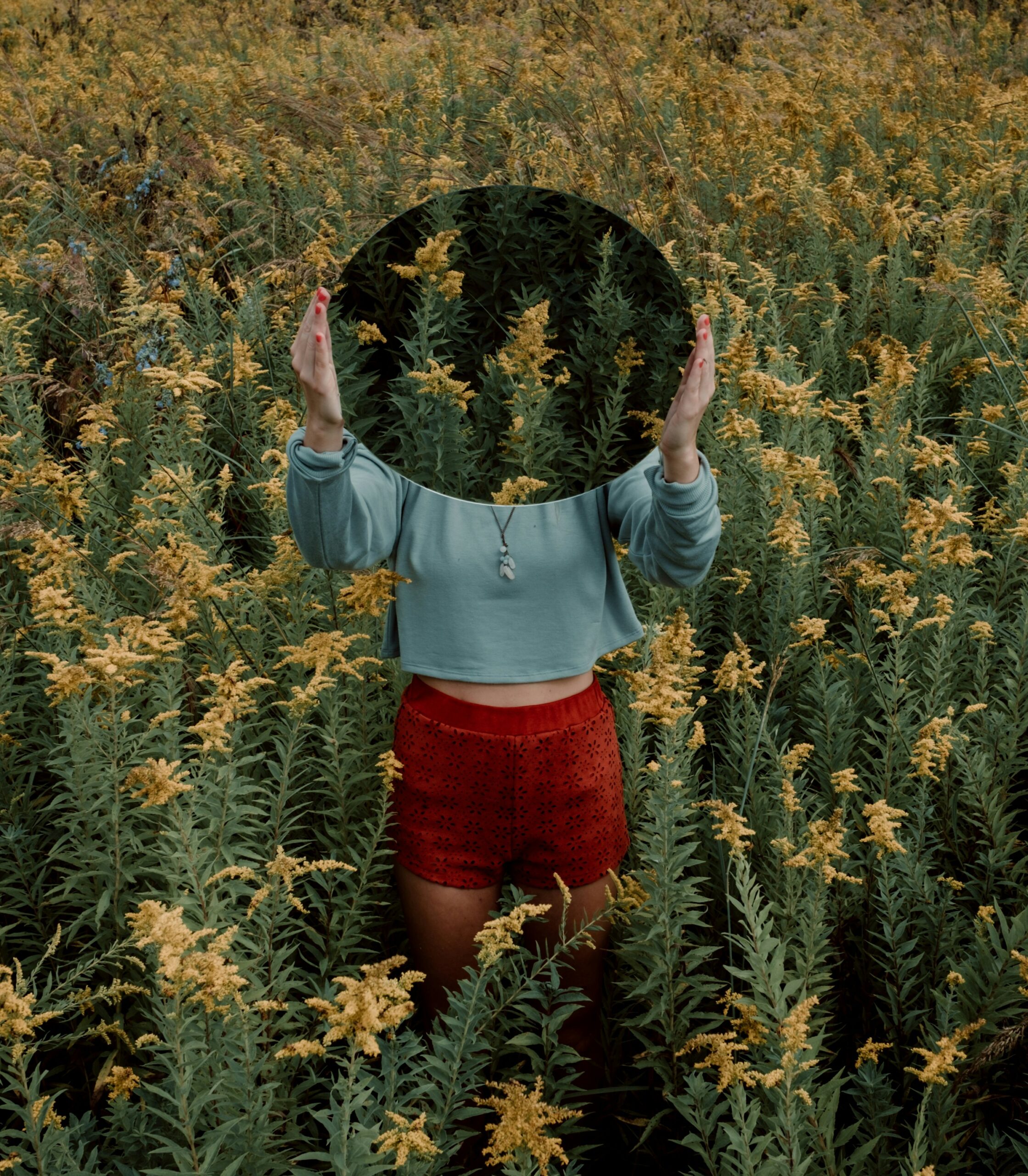 standing woman surrounded by yellow flower field during daytime